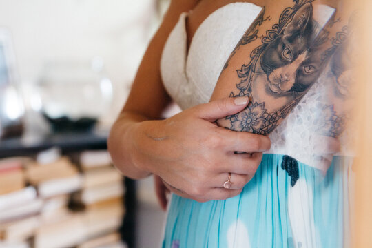 young female with tattoos looking in mirror wearing dress