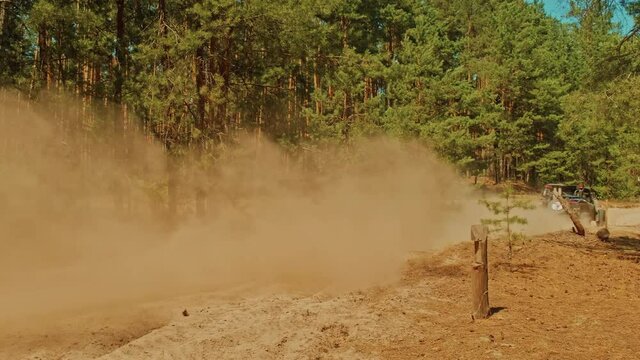 Cinematic clip of a buggy car going in cross country road. Fast buggy is driving with big clouds of dust. Speed riding of a racing off-road car in the forest road, with a sound of engine.