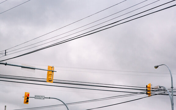 Three stoplights on a busy intersection with overcast sky as background