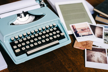 retro blue typewriter surrounded by inspirational items, polaroids, books, ipad and a notepad, with