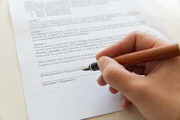 Close up of hand signing document.