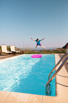 Boy jumping onto inflatable in swimming pool