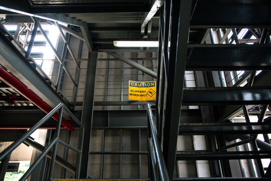 Caution Slippery When Wet warning sign in carpark steel stairways