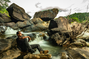 man relaxing at rock with the beautiful waterfall stream long exposure shot at evening
