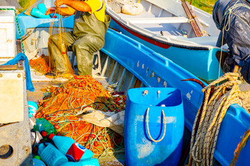 Fisherman empties fish from net in his small boat