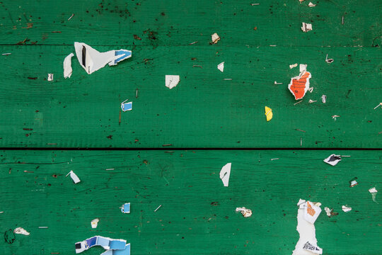 Green wooden background with remains of information leaflets