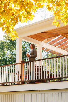 Woman on Porch Enjoying Morning Coffee in Autumn
