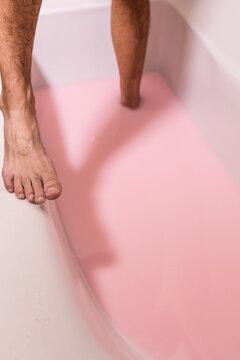 bathe,a man in a bathtub filled with pink water,legs