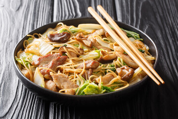 Tasty Cellophane noodles with fried pork belly, shiitake and napa cabbage in soy sauce close-up in a plate on the table. Horizontal