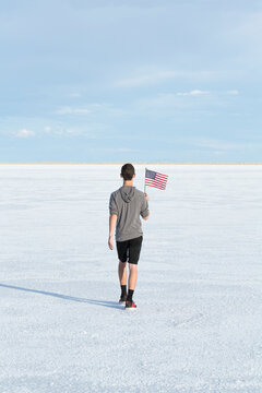 Portrait of young male waving an american flag in the salt flats of Utah