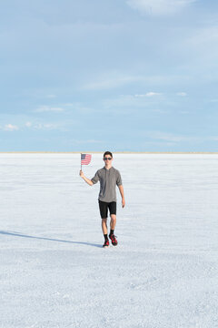 Portrait of young male waving an american flag in the salt flats of Utah