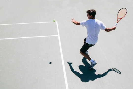Tennis player moments before hitting the ball in a tennis court seen from above