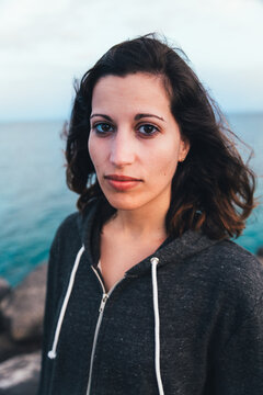 Portrait of a young woman on a pier looking at camera and wearing a grey sweatshirt