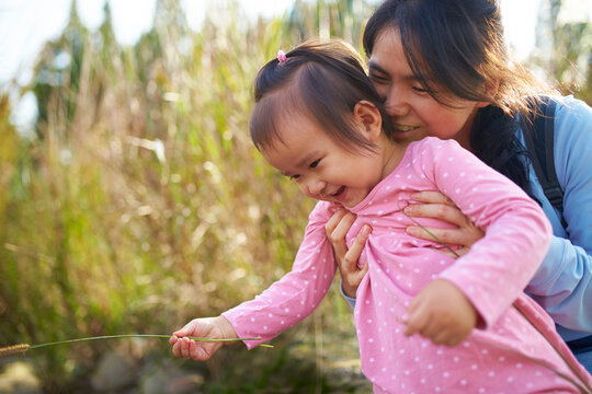happy little asian girl playing with her mother smile in her mother's lap