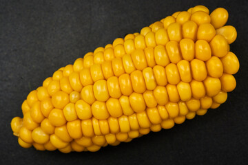 boiled ear of corn on black background