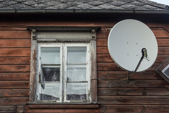 Traditional wooden house in decay with modern satellite dish