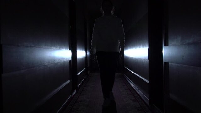 Woman silhouette walks in the dark corridor slow motion