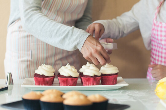 Closeup of the hands of a mother and daughter making cupcakes