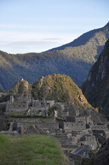 Fototapeta na wymiar The stone houses and ruins inside the lost city of Machu Picchu, as seen in the early morning light