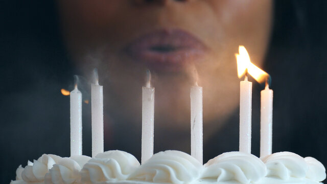 Close Up On Candles As Woman Blows Out Flames