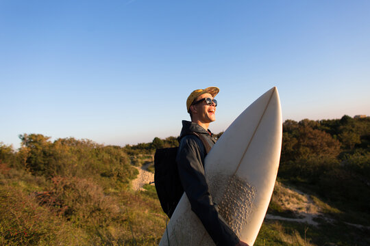 A surfer with his board in the dunes.