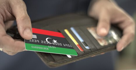 Man pulls credit card with flag of Libya out of his wallet, fictional card number