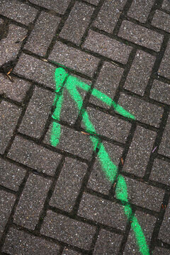 Green arrow painted on a brick road, pointing forwards