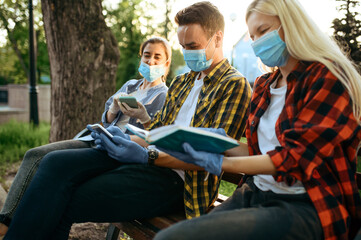 Young people in masks sitting on bench, quarantine