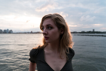 Young model standing by the water with the sun setting