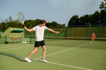 Male tennis player with racket hits the ball