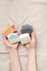 Woman holding natural handmade soap bar on linen fabric background