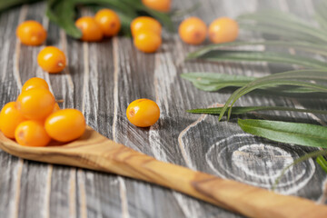 Sea buckthorn in wooden spoon. Fresh ripe berry with leaves isolated on black and white background with copy space for your text.