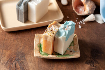 Natural handmade soap bar in ceramic soap dish with spa accessories on wooden table
