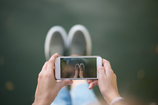 girl taking a photo feet on the lake