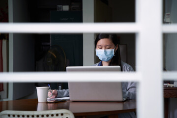 Asian girl doing homework at home. The school has been closed during coronavirus outbreak and the classes have moved to e-learning platform.