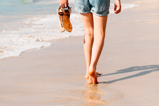a teenager walking barefoot at the beach