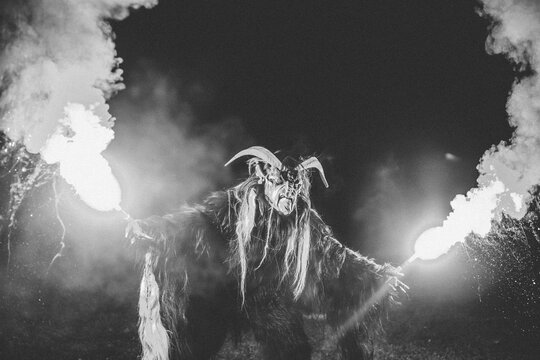 portrait of a krampus with burning bengal lights