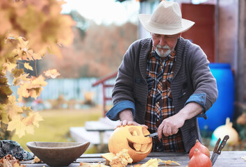 Autumn traditions and preparations for the holiday Halloween. A house in nature, a lamp made of pumpkins is cutting out at the table.