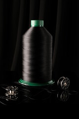 Bobbin of thread on a black background, illuminated from the side