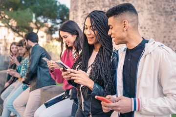 Group of teenagers talking, bonding together and viewing social media contents on the smartphone screen. Focus on the beautiful African descent girl with the dreadlocks hair.