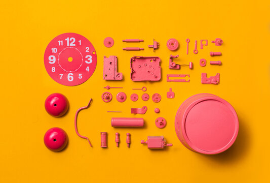 Organised Disassembled Clock/pink parts on orange background