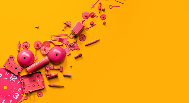 Disassembled pink clock on orange background.