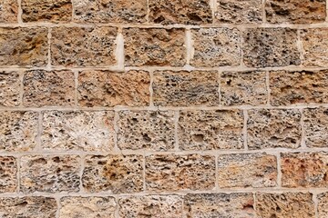 A wall formed by spongy textured bricks attached with cement solution along with different color tones