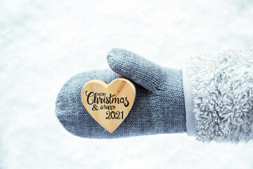 Heart With English Calligraphy Merry Christmas And A Happy 2021. Hand In A Glove With Fleece And Snow.