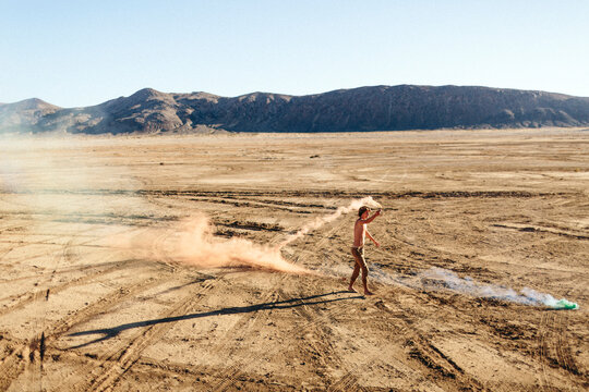 Young man running with Fireworks in the desert