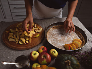 Preparation, celebration of Thanksgiving. The cook lays a layer of apples on the surface of the dough. Making a traditional apple pie.