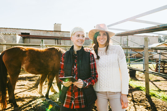 Women farmers standing on farm holding a digital tablet.