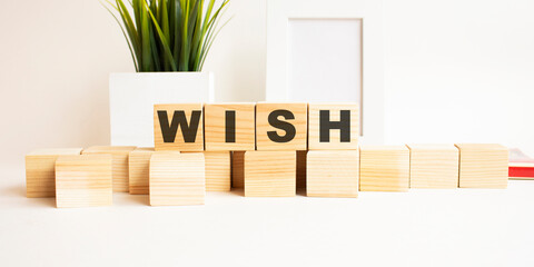 Wooden cubes with letters on a white table. White background with photo frame and house plant.