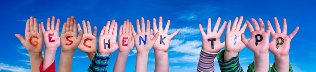 Children Hands Building Colorful German Word Geschenk Tipp Means Gift Tip. Blue Sky As Background