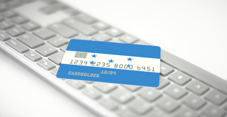 Plastic bank card depicting flag of Honduras on computer keyboard. Fictional numbers